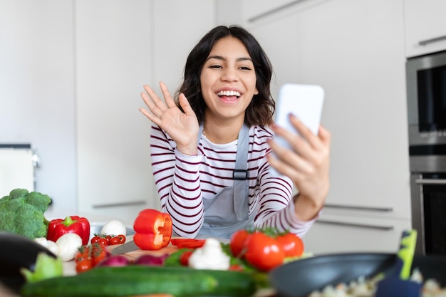 Vrolijke mooie brunette Spaanse vrouw influencer streaming tijdens het koken