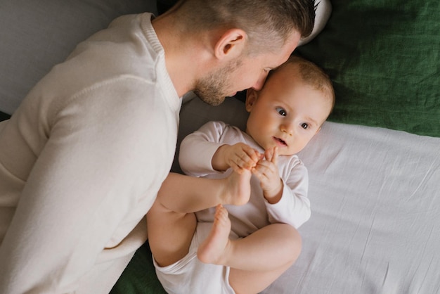 Vrolijke mooie pas gemaakte vader en een charmante baby van zes maanden liggen samen op groen