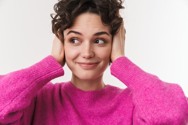 Vrolijke mooie vrouw lacht en bedekt haar oren geïsoleerd over witte muur