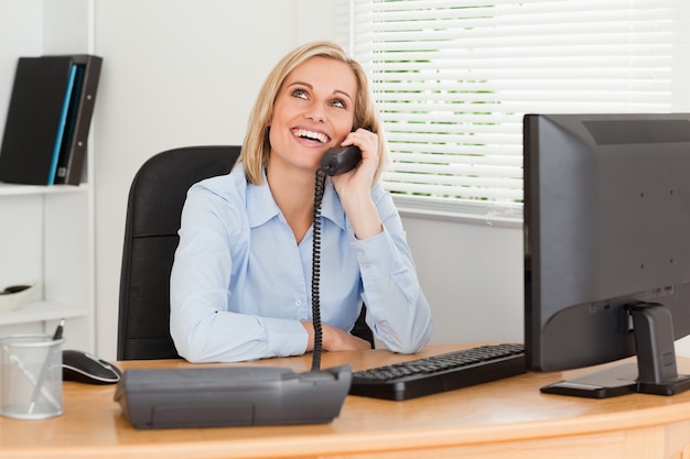 Vrolijke onderneemster op telefoon die het plafond bekijkt