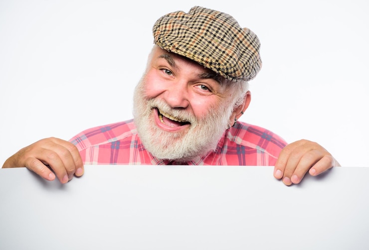 Vrolijke opa zoeken naar een baan Hulp nodig gezocht Kopieer ruimte informatie tevreden volwassen man in retro hoed Advertentie Advertentie winkel Senior bebaarde man plaats aankondiging op banner