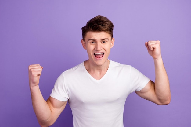 Vrolijke opgewonden man met een leeg t-shirt dat geïsoleerd staat over een lichte achtergrond en succes viert