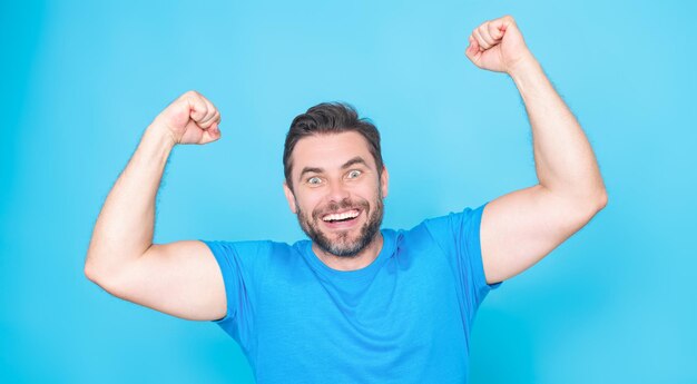Vrolijke opgewonden man viert succes over studio blauwe geïsoleerde achtergrond opgewonden winnaar opgewonden