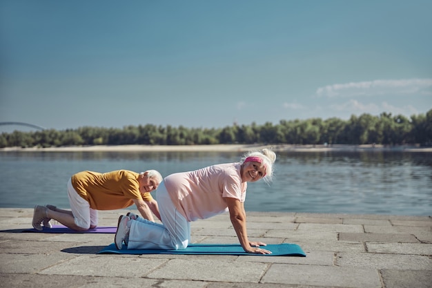 Vrolijke oudere blanke vrouw en een man poseren voor de camera tijdens de yoga-workout