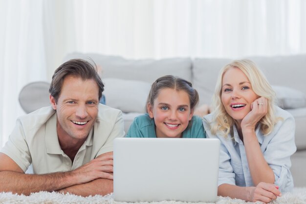 Vrolijke ouders en dochter die laptop met behulp van