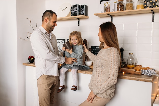 Vrolijke ouders en hun schattige dochter meisje in keuken thuis.