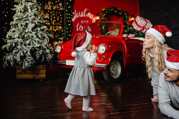 Vrolijke ouders met dochter op kerstmuts thuis met kerst achtergrond