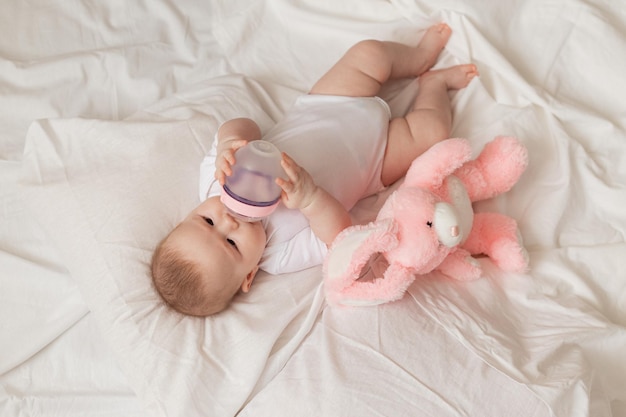 Vrolijke pasgeboren baby die melk of melkvoeding uit een fles drinkt producten voor kinderspeelgoed