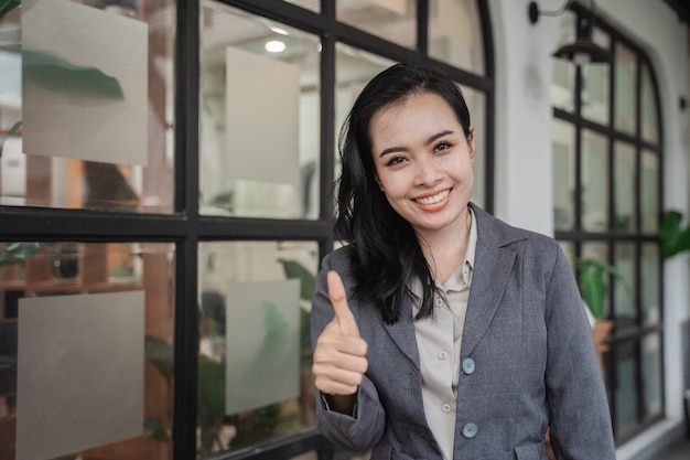 Vrolijke portret van jonge Aziatische zakenvrouw duimen opdagen in een café