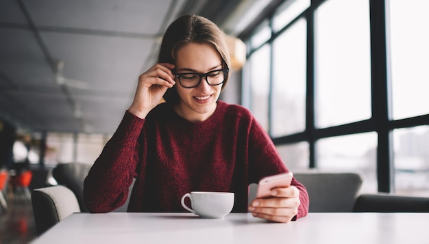 Vrolijke positieve blanke student die e-mail controleert via een modern elektronisch apparaat dat is aangesloten op wifi