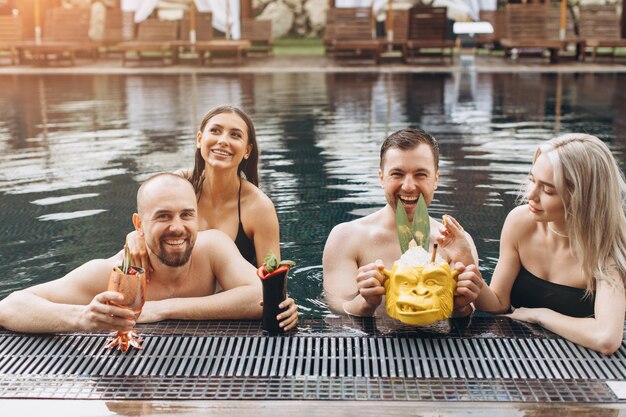 Vrolijke positieve groep vrienden die in de zomer ontspannen en zwemmen in het zwembad