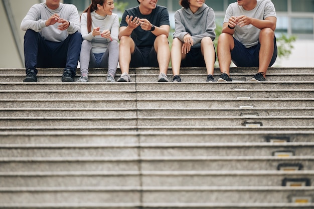 Vrolijke positieve jonge aziatische mensen die buiten zitten na het joggen in de ochtend en de voordelen van een actieve levensstijl bespreken