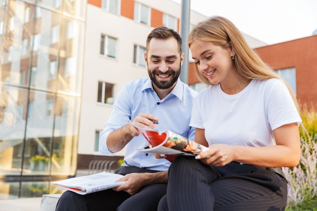 vrolijke positieve jonge studenten collega's op straat studeren met voorbeeldenboeken.