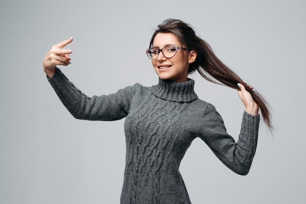 Vrolijke schattige brunette in glazen met vredesteken