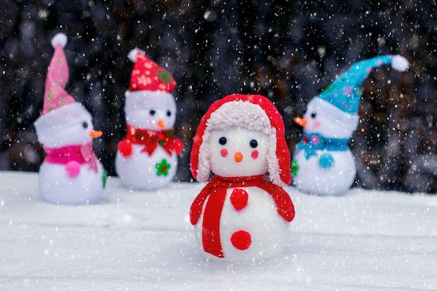 Vrolijke sneeuwmannen in het bos in de sneeuw op een donkere achtergrond tijdens een sneeuwval