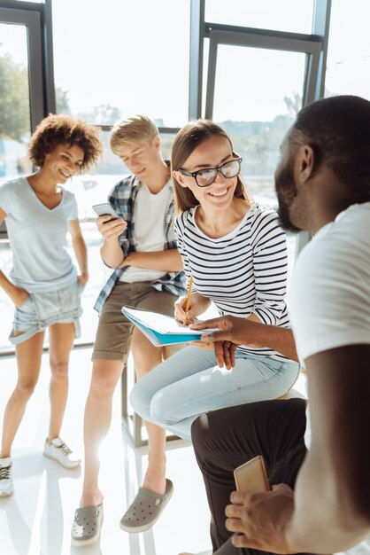 Vrolijke stemming. gelukkige jonge internationale studenten die rusten na de universiteit en een pauze hebben terwijl ze genieten van communicatie