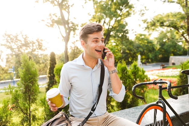 Vrolijke stijlvolle jongeman praten op mobiele telefoon