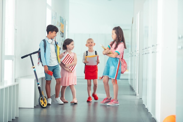 Vrolijke stijlvolle kinderen die samen naar de klas gaan