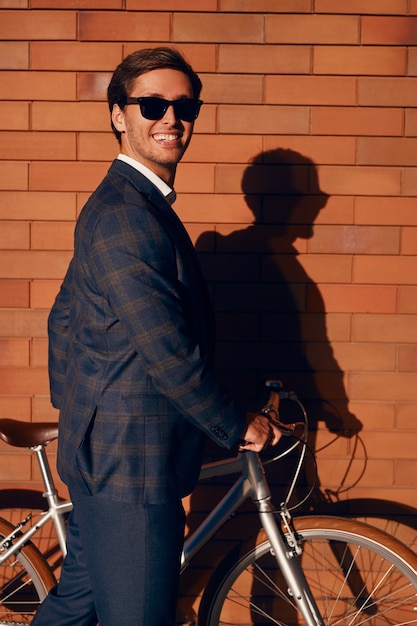 Vrolijke trendy zakenman met fiets in de stad