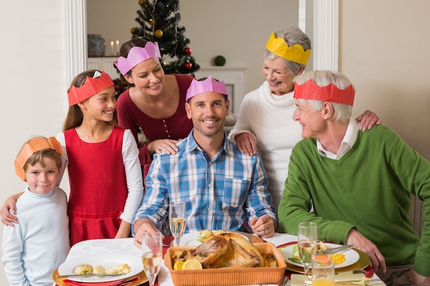 Foto vrolijke uitgebreide familie in feestmuts aan tafel