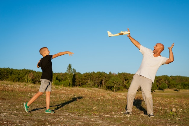 Vrolijke vader en zoon spelen per vliegtuig in de natuur