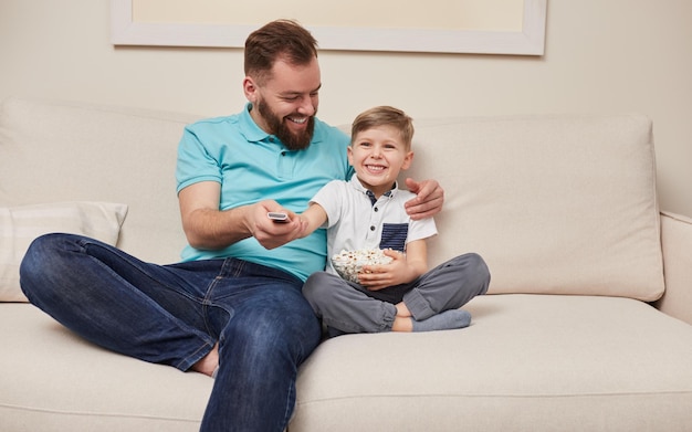 Vrolijke vader en zoon thuis tv kijken