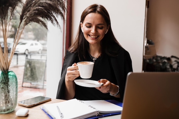 Vrolijke verraste vrouw glimlacht en kijkt naar het bedrag van de inkomensinkomsten salaris en verheugt zich Gelukkig meisje verheugt zich in het winnen en zitten achter laptop in café