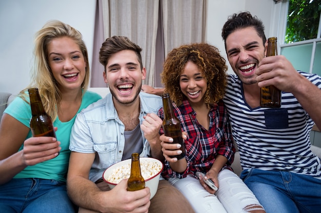 Vrolijke vrienden die van bier genieten terwijl thuis het letten van op wedstrijd