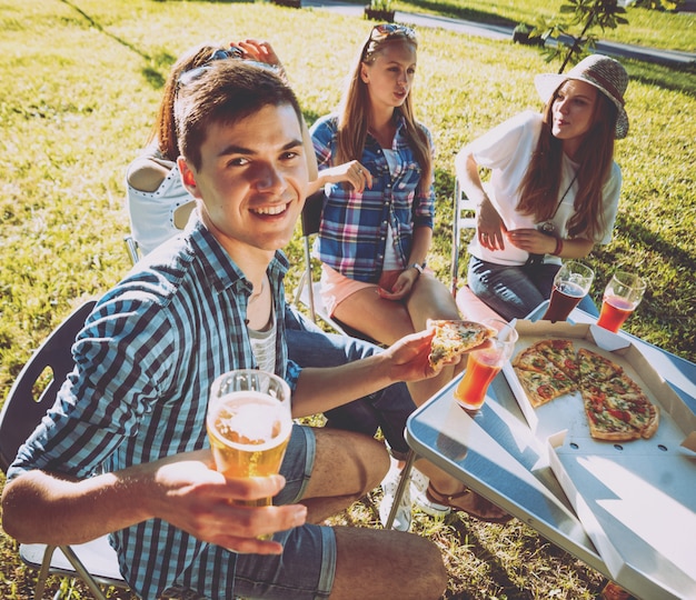 Vrolijke vrienden op picknick in het park. Pizza eten