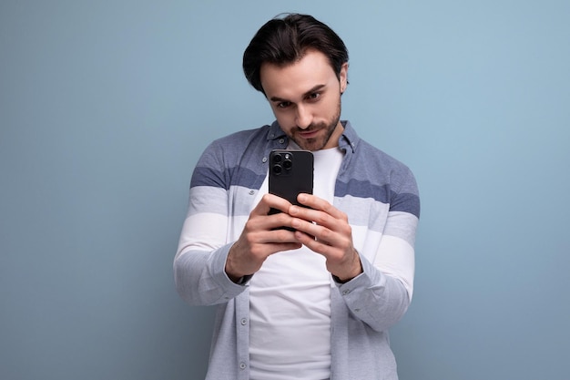 Vrolijke vrolijke brunette man in casual stijl neemt foto met behulp van telefoon