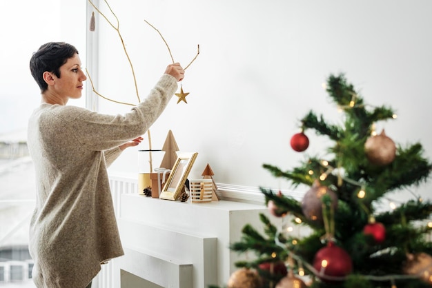 Vrolijke vrouw die een kerstboom versiert met ornamenten