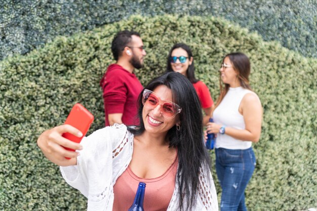 Vrolijke vrouw die een selfie neemt in de buurt van vrienden