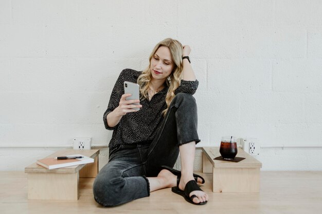 Vrolijke vrouw die haar telefoon gebruikt in een café