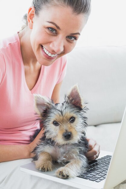 Vrolijke vrouw die laptop met haar terriër van Yorkshire met behulp van