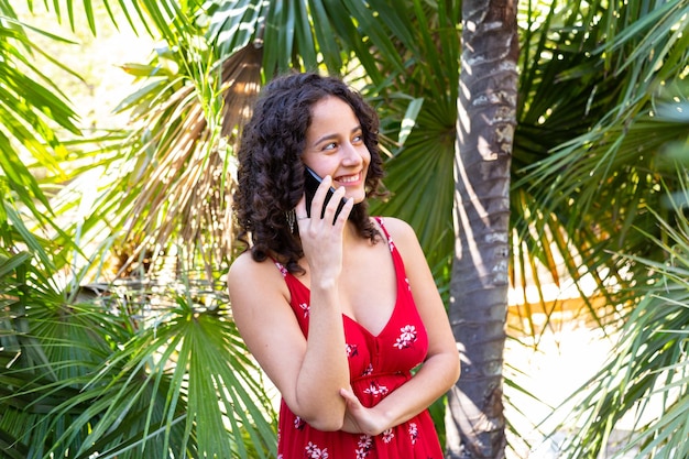 Foto vrolijke vrouw die op smartphone in park spreekt