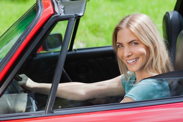 Vrolijke vrouw die rode cabriolet drijft