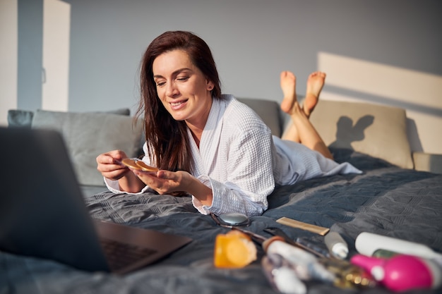 Vrolijke vrouw die schoonheidsprocedures thuis doet