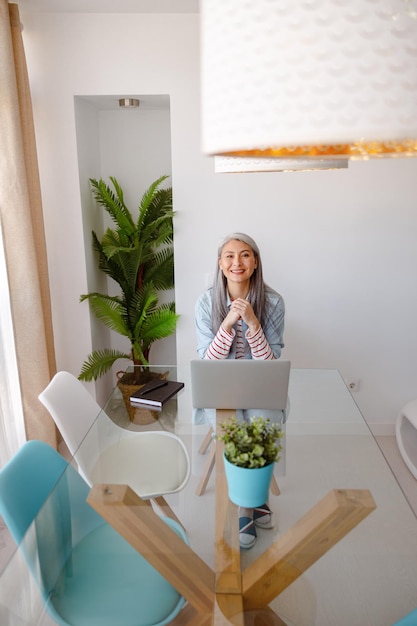 Vrolijke vrouw die thuis aan tafel zit met een notitieboekje