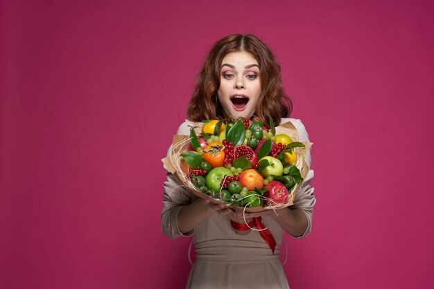 Vrolijke vrouw glimlach poseren vers fruit boeket emoties studio model