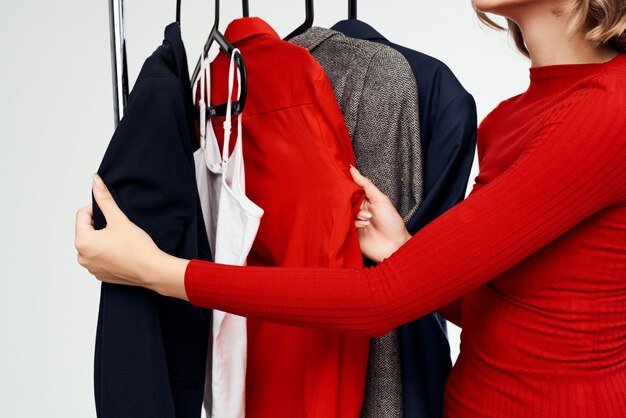 Foto vrolijke vrouw in een rood jasje dichtbij de lichte achtergrond van de garderobe kleinhandels