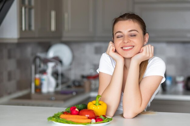 Vrolijke vrouw koken groentesalade in moderne keuken