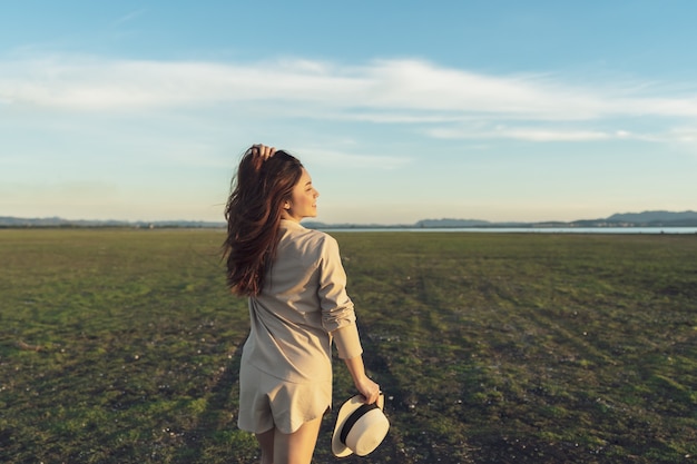 Vrolijke vrouw loopt over het groene veld met zonlicht