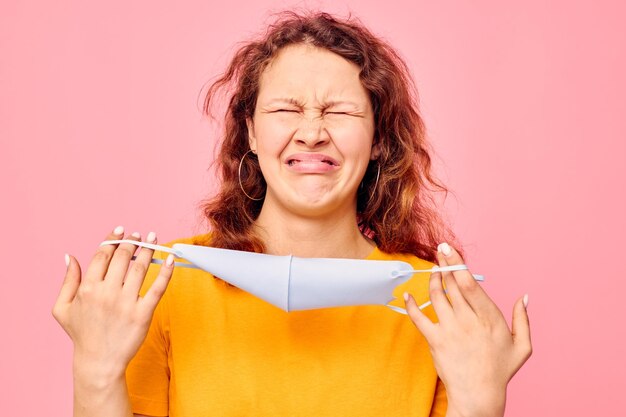 Vrolijke vrouw medisch gezichtsmasker grimas emoties close-up roze achtergrond ongewijzigd