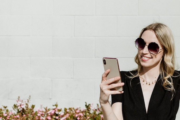 Vrolijke vrouw met een zonnebril die haar telefoon gebruikt