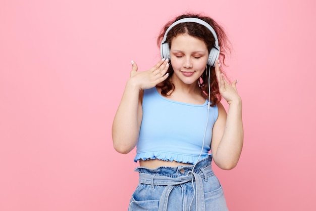 Vrolijke vrouw met koptelefoon muziek poseren roze achtergrond