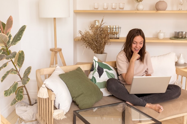 Vrolijke vrouw met laptop op de bank