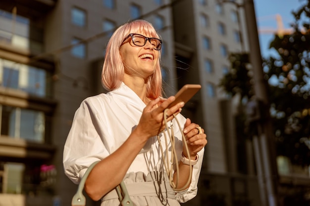 Vrolijke vrouw met mobiele telefoon die op straat staat