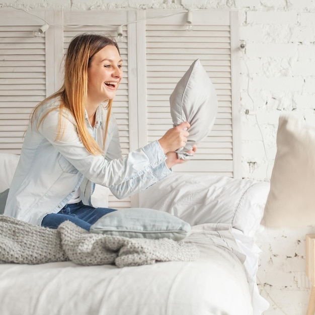 Vrolijke vrouw met plezier thuis. Beweging, Kussengevecht