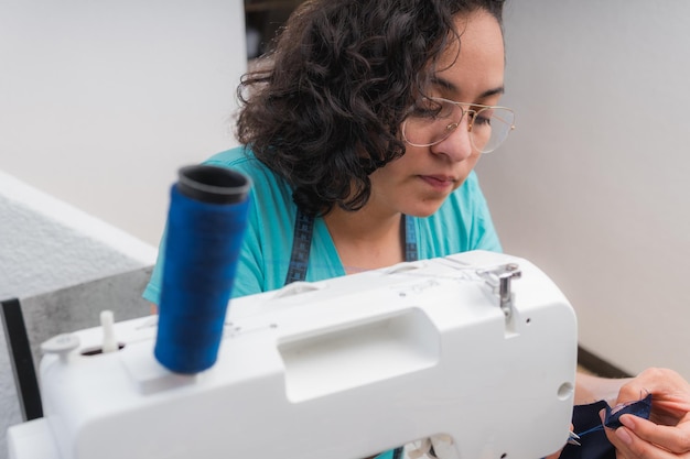 Vrolijke vrouw naait zittend op haar werkplek in mode workshop