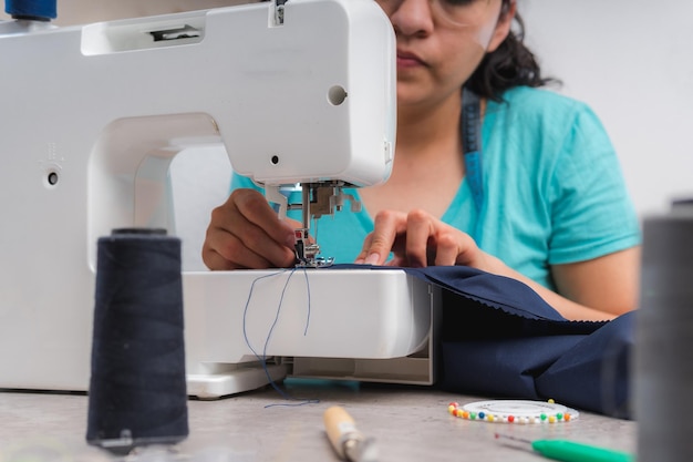 Vrolijke vrouw naait zittend op haar werkplek in mode workshop